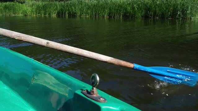 The boat is floating on the water. Oars in the water. The concept of a summer vacation in nature.