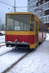 Naklejka na ściany i meble A city tram rides on snow-covered rails on a winter day