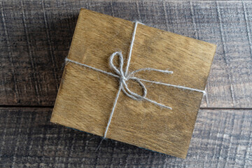 Dark wood box with a rope on a wooden background, closeup