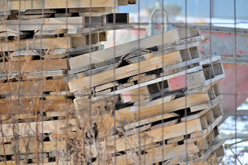 A pile of used pallets on a construction site on a winter day