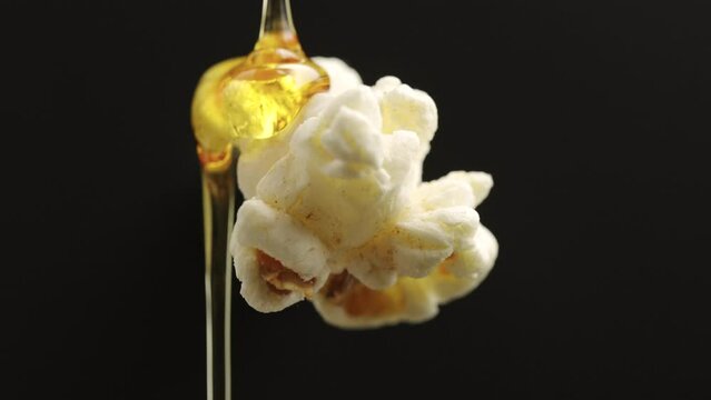caramel dripping pop.flavor sweet popcorn.appetizing sweet snack  on black background.
slow motion dripping popcorn.