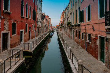 Fototapeta na wymiar A canal in venice with a red building and a blue sky