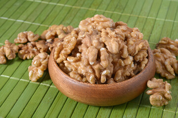 Walnuts in a plate on a brown wooden background. Nuts are a source of vegetable protein.