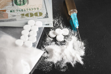 Drugs on dark background, cocaine or heroin white powder, white pills, syringe with a dose and us...