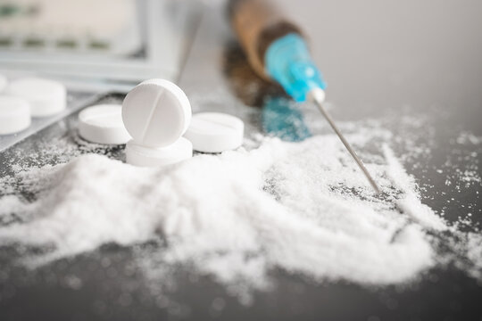 White pills, drugs or medical treatment, cocaine or heroin white powder, syringe with a dose and us dollar cash. Drug abuse and addiction concept