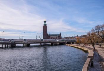 Fototapeta na wymiar Train and motor way bridge, pier walkway and skyline with the Town City Hall, an early spring sunny day in Stockholm