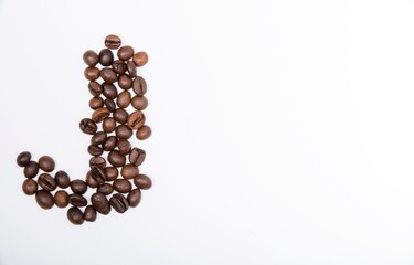 J is a capital letter of the English alphabet made up of natural roasted coffee beans that lie on a white background. Plenty of space to put text or pictures, top view and studio photography.