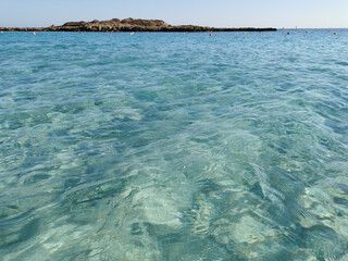 Obraz premium Fig Tree Bay beach, crystal clear water, white sand at the bottom, small island off the coast.
