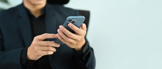 Cropped image of businessman in black suit using smart phone. Copy space for your advertise text