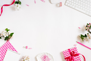 Modern women's desktop of a blogger or freelancer with a keyboard, apple blossoms, an office, a gift and a notebook with a copy space. Flat lay