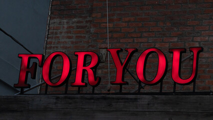 Red lettering for you sign against a brick wall loft style