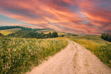 Beautiful mountains, framed by orange sun, burn with bright fire against a golden sky in a western sunset.