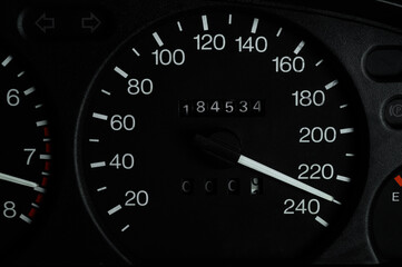 Black car panel, speedometer shows 230 km h, close-up. Speedometer needle shows maximum speed.High speed concept.