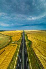 Aerial view over A2 highway road in Dobrogea, Romania, in an agriculture fields landscape with...