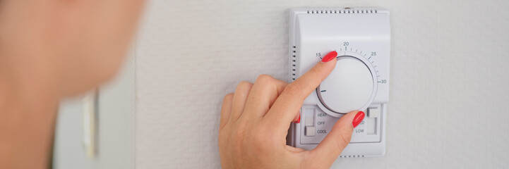 Hand adjusts button of the control unit of heating and cooling system of house closeup