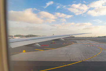 Wing of an airplane jet flying and landing with buildings view in urban city from window at runway in the airport. Traveling and transportation concept.