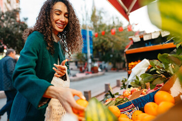 Young woman consumer choosing products to buy from local farmers market stand