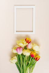 A bright spring bouquet of tulips and a text frame on a beige background with copy space. Flat lay greeting card