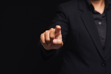 Businessman in a suit finger pointing while standing on a black background in the office