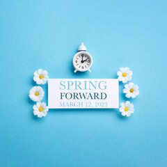White Alarm Clock and Spring Daisy Flowers on Blue Background - obrazy, fototapety, plakaty