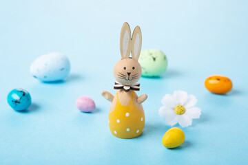 White Easter Bunny, Easter Eggs and Spring Flowers on Blue Background