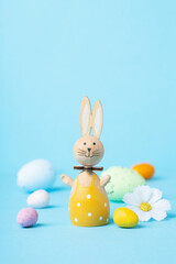 Wooden Easter Bunny, Easter Eggs and Spring Flowers on Blue Background