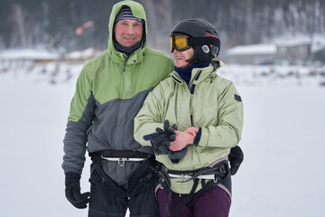 Husband and wife, snowsurfers, middle-aged people, standing and laughing. They have a great mood after snowsurfing.