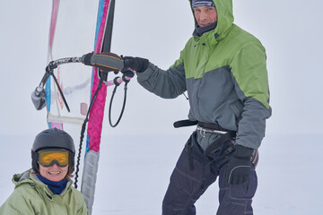 Husband and wife, snowsurfers, middle-aged people, standing and laughing. They are in a great mood after snowsurfing on a cloudy winter day.