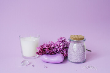 Obraz na płótnie Canvas Spa setting with lilac flowers. Sea salt in a glass jar, soap and candle on the background