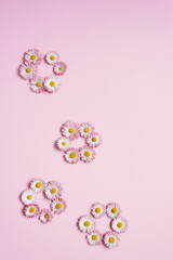 Daisy flowers are folded into flower shapes on a pink background. Flat lay, copy space