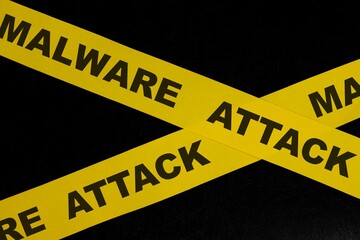 Malware attack cybercrime alert, caution and warning concept. Yellow barricade tape with word in dark black background.