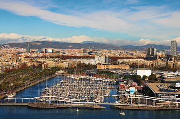 Fototapeta premium Amazing aerial landscape of historic part of Barcelona during sunny day. Embankment, harbor with moored yachts on the foreground. View from the cable car. Travel and tourism concept