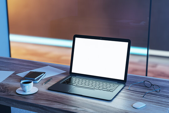 Top perspective view on blank white modern laptop screen with space for your web design or landing page on wooden table with coffee cup and office tools on blurred background. 3D rendering, mock up