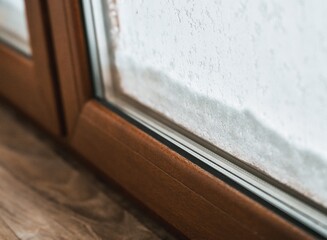 brown PVC window close-up during snowy weather. cozy indoors protected with good quality windows while keeping warm air inside the house. triple-glazed PVC