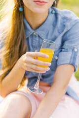 Glass of orange juice in the hand of a young woman
