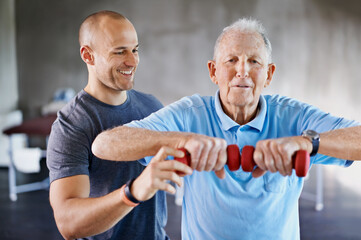 Im impressed with your progress. Shot of a physiotherapist helping a senior man with weights.