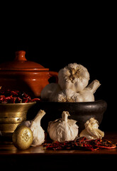 Still life of dried red chilies peppers and garlics with pestle and mortar against black background