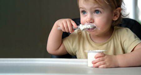 Young Kid Eating Blend Mashed Feed Sitting in High Chair. Baby Weaning. Little Girl Learning to Eat...