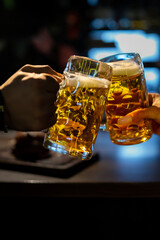 man and woman hands clinking glasses of light beer at the pub or bar