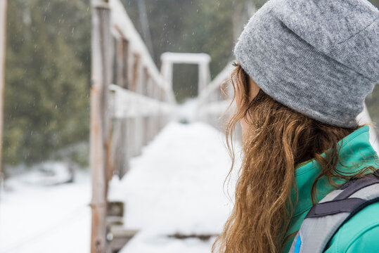 Woman looking at footbridge in forest in winter