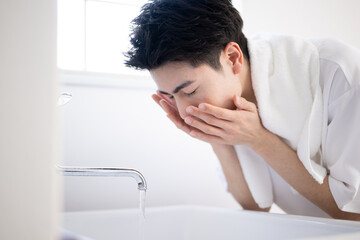 Obraz na płótnie Canvas A man washing his face at a washbasin Close-up