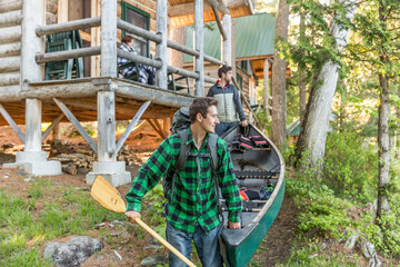 Two Men Carry A Canoe Past The Cabins At The Lodge Near Greenville, Maine