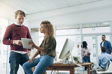 Producing results with just a few taps. Shot of two young colleagues using a digital tablet together in a modern office.
