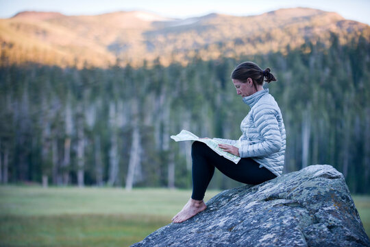 A woman, endurance athlete sits on a boulder in Big Meadow.