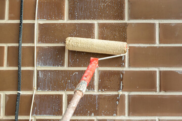 Primer on the brick wall with a roller.
