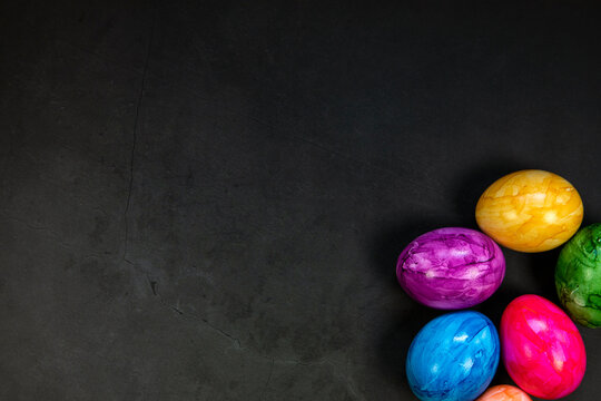 Stylish background with colorful painted easter eggs isolated on dark concrete background for web design. Flat lay, top view, mockup, overhead copy space Happy Easter concept