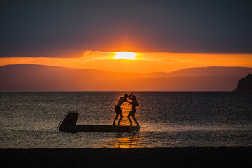 Young man and woman play fighting on floating platform in Lake Taupo, Kinloch, Waikato, New Zealand