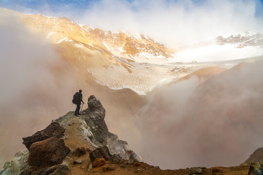 Man standing on rock formation in mountains, Mutnovsky, Kamchatka Peninsula, Russia