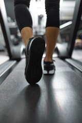 Fototapeta premium Close up of sole of sneakers of unrecognizable athlete jogging on a treadmill.