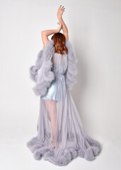 Naklejka premium Portrait of beautiful red haired woman wearing glamorous fluffy bridal dressing gown and vintage pearl necklace. Elegantly standing pose, isolated on white studio background.